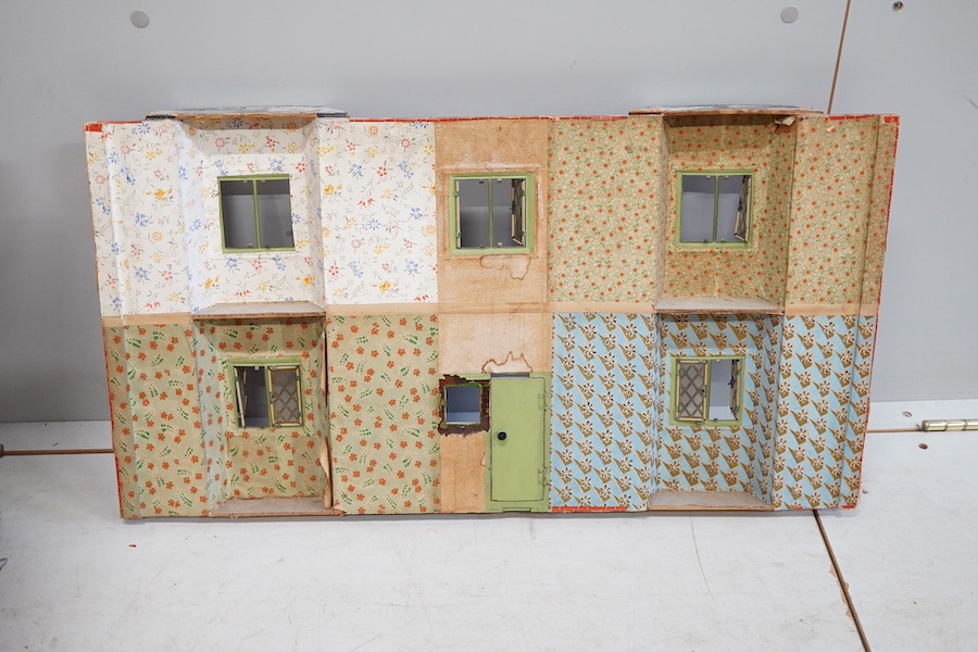 A 1920s/30s commercially produced dolls house, possibly by Tri-ang, of plywood construction, overlaid with printed paper roof tiles and brickwork, and tinplate windows and window frames, comprising of four rooms with bay